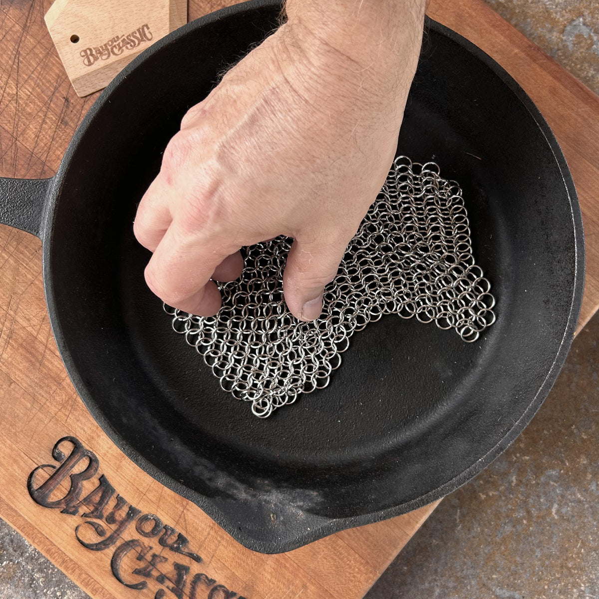 Person using chainmail scrubber in a cast iron skillet