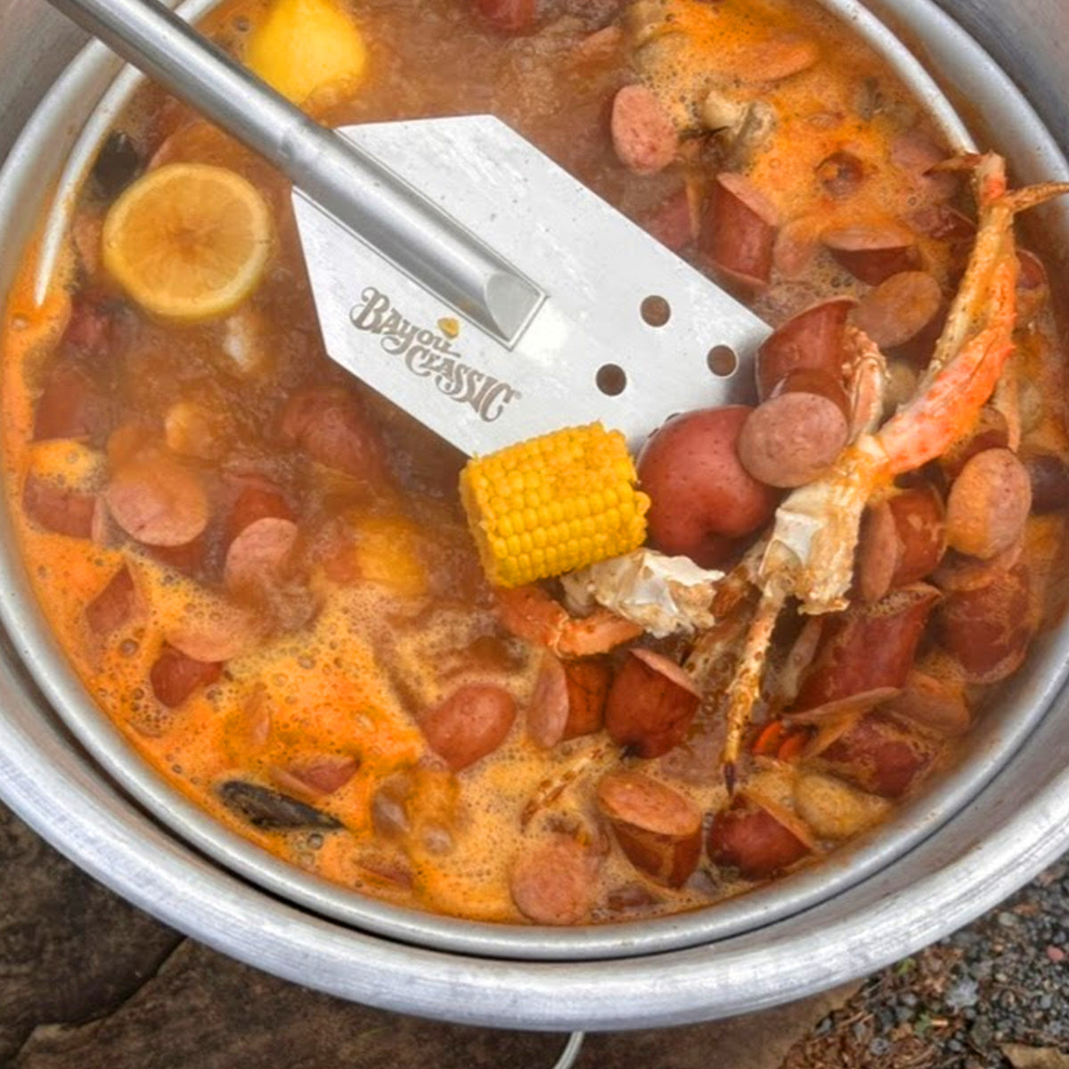 Boiled seafood and sausage pot with a stainless paddle, featuring Bayou Classic branding.
