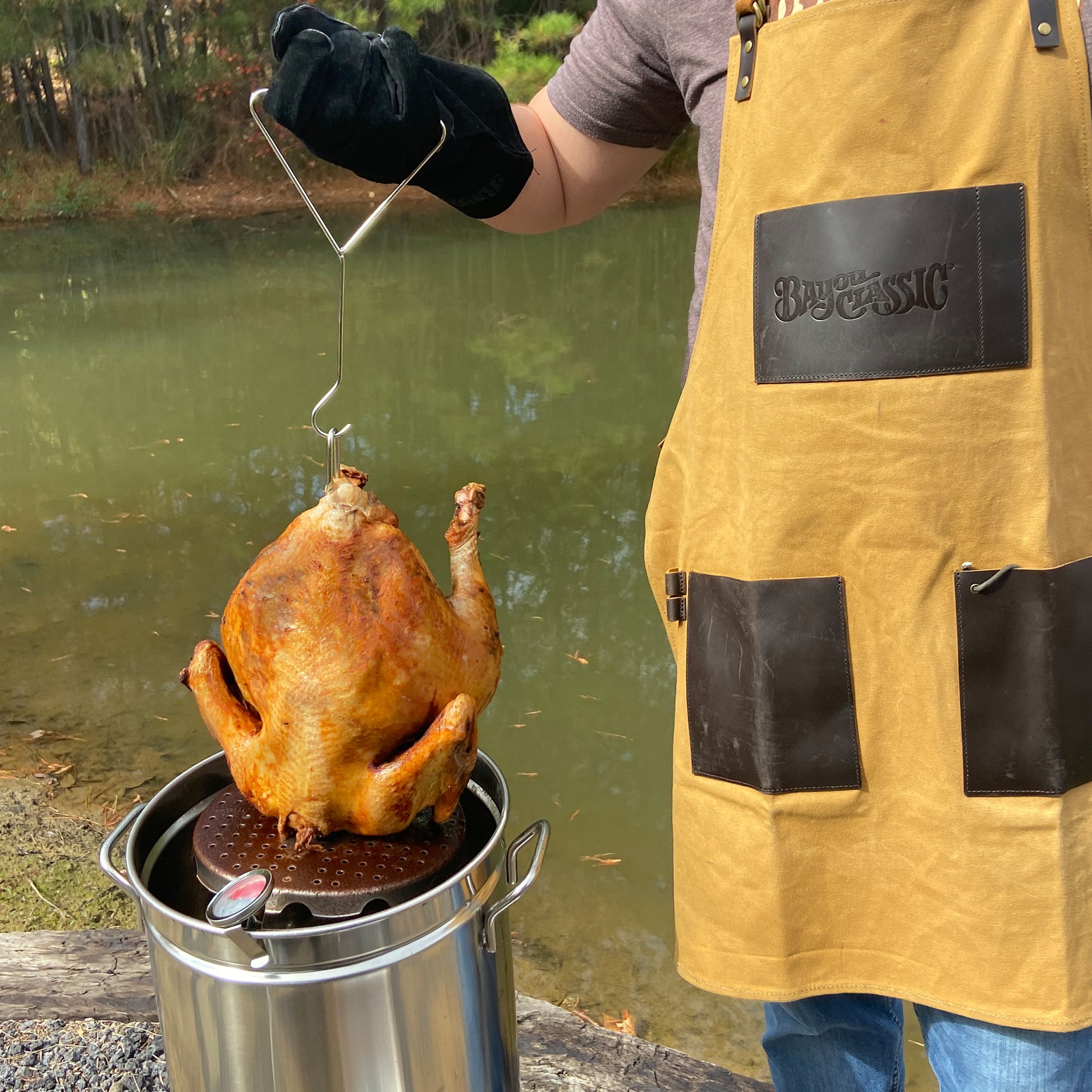 Person wearing an apron frying a turkey outside