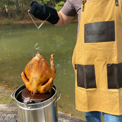 Person wearing an apron frying a turkey outside
