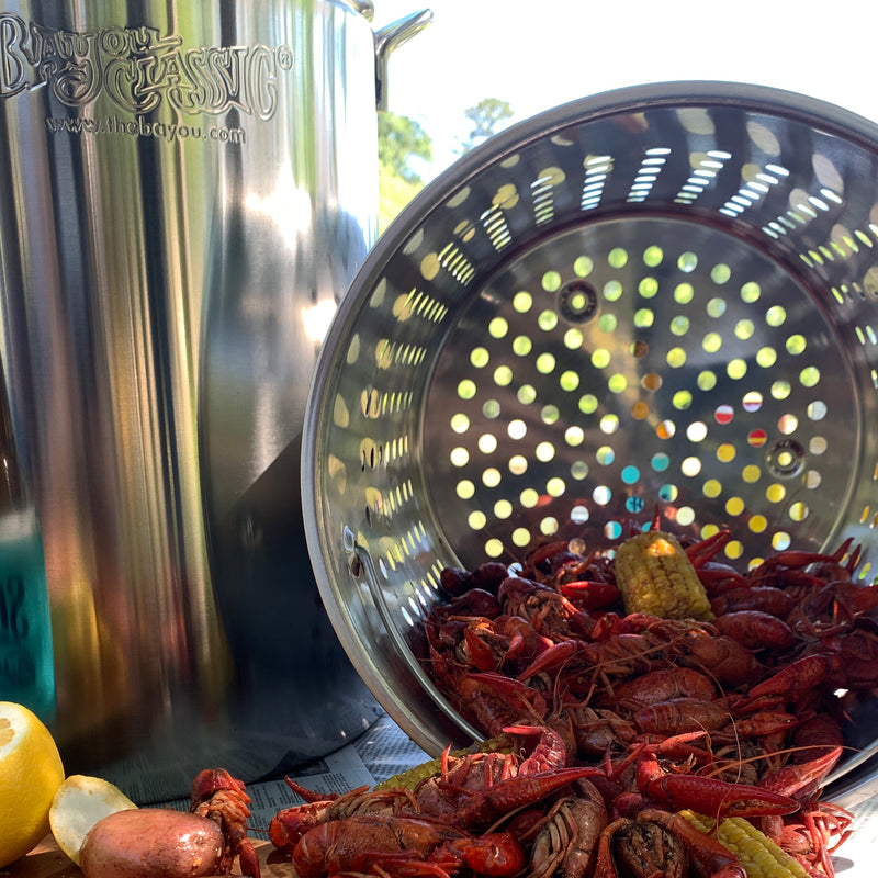 Stainless Steel Stockpot with basket dumping out crawfish in an outdoor setting