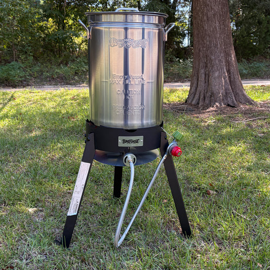 A stainless steel turkey fryer pot on a steel  cooker in an outdoor setting.