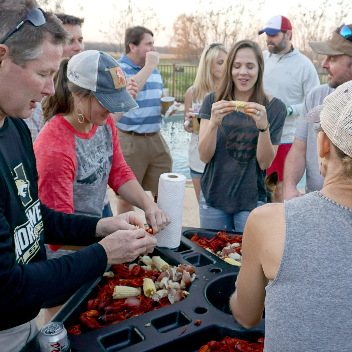 Plastic seafood event table with people standing around eating crawfish