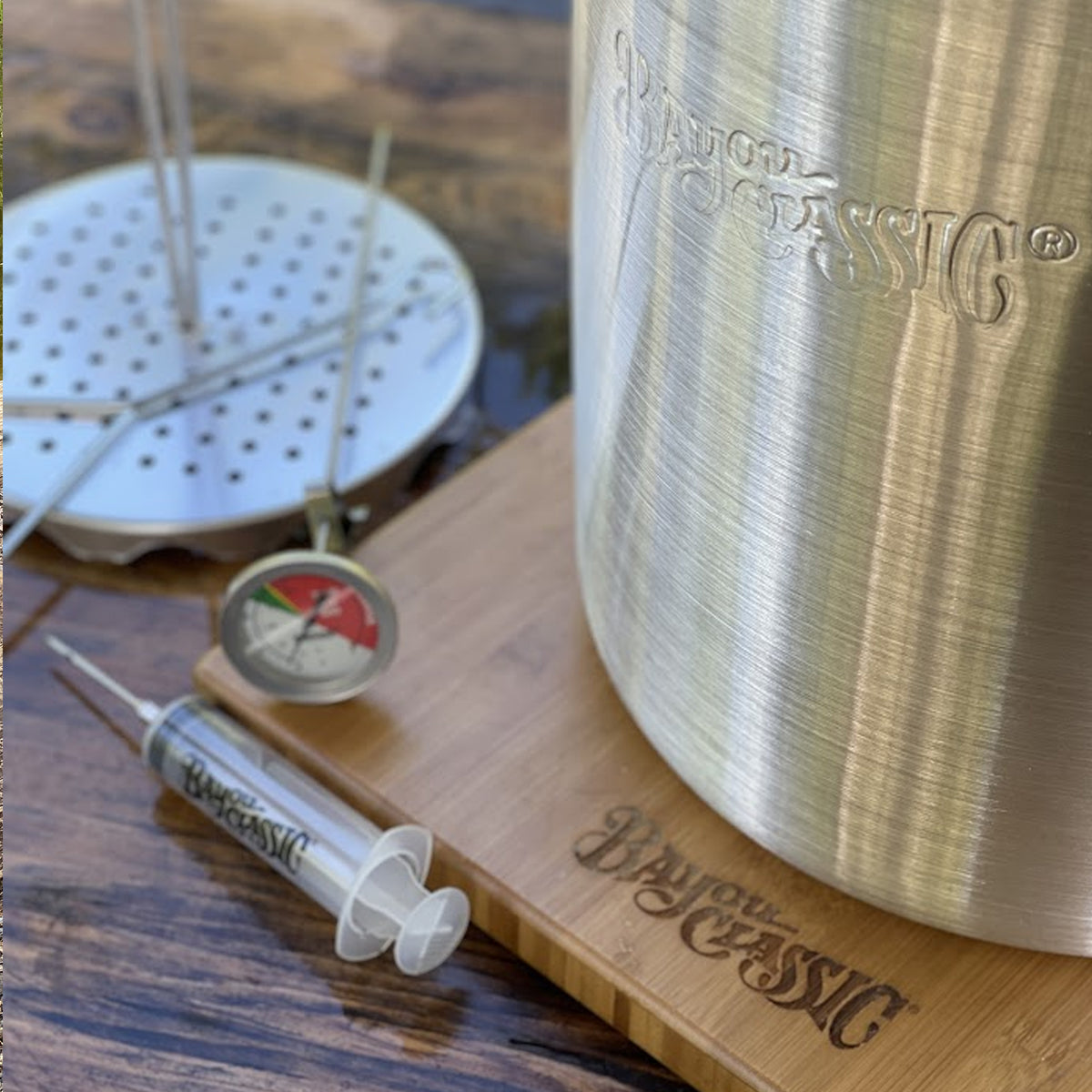 Close up image of aluminum turkey fryer with accessories on a wooden surface