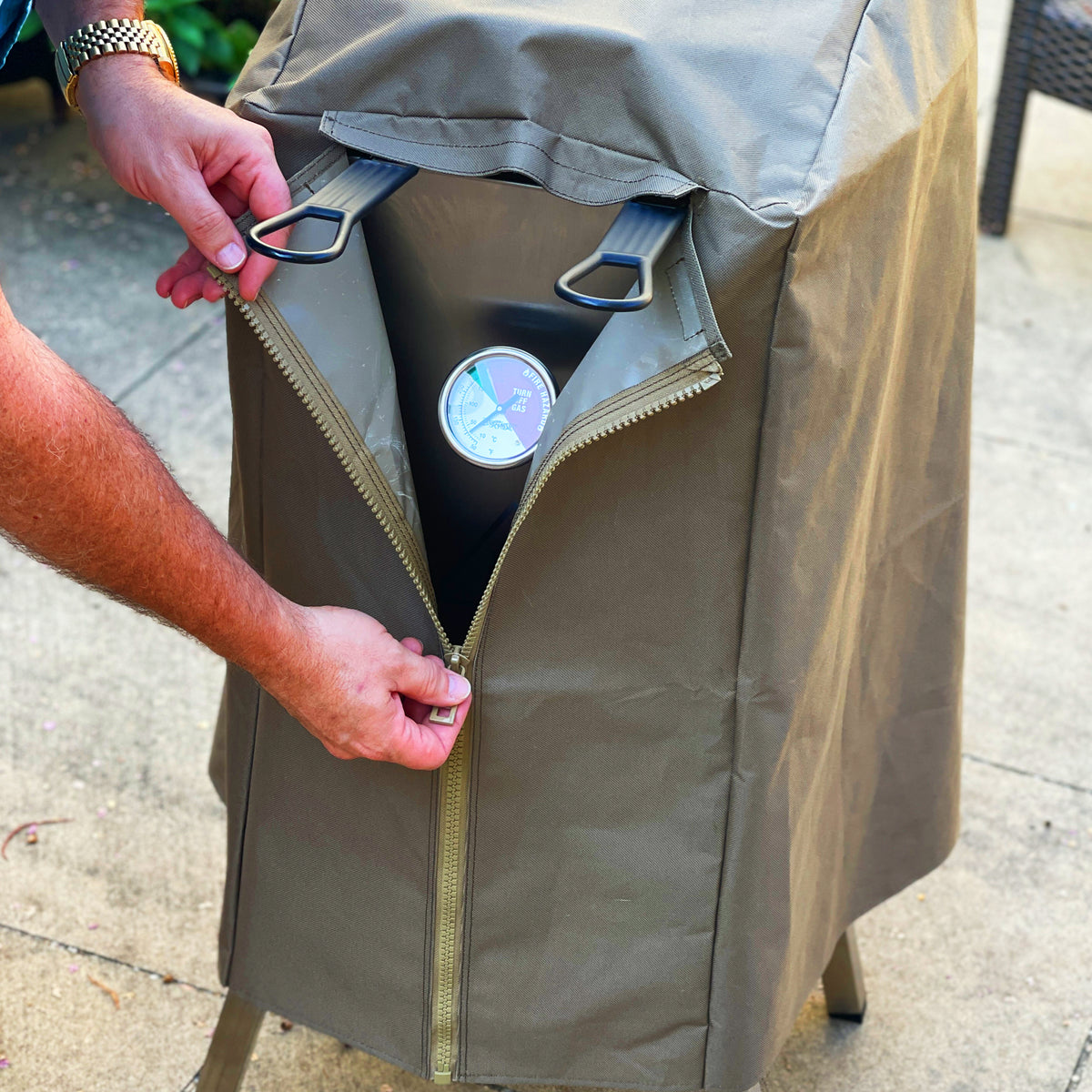 Man unzipping brown canvas cover to the 4-gal Bayou Fryer