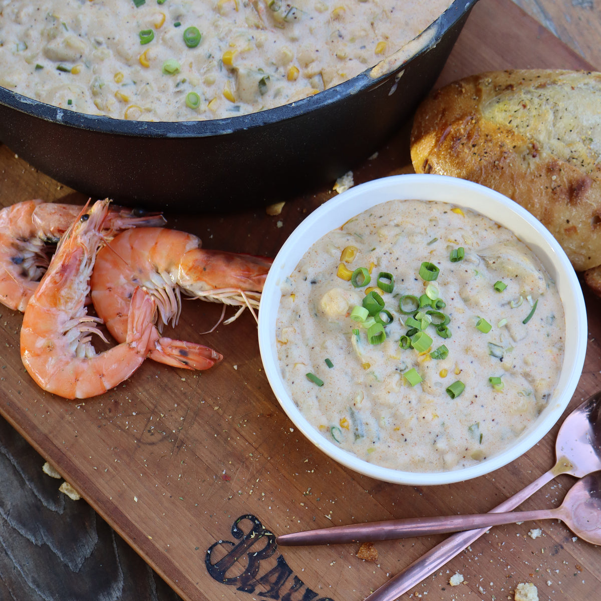 Chowder in a cast iron pot and bowl with shrimp and bread