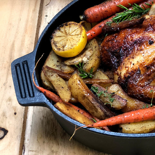 Overview with roasted chicken, potatoes, and carrots on a wooden surface
