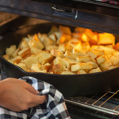 Cornbread dressing in a cast iron skillet being put into an oven