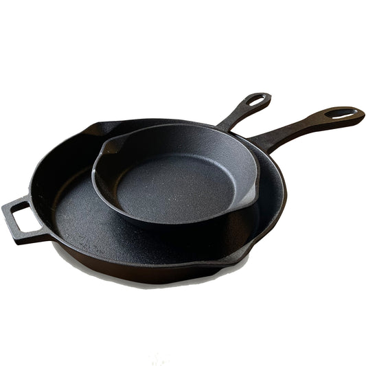 A set of two black cast iron skillets, one larger than the other, stacked inside each other on a white background.