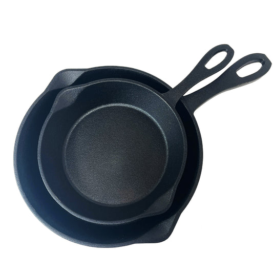 A set of two black cast iron skillets, one larger than the other, with pouring spouts on the sides.