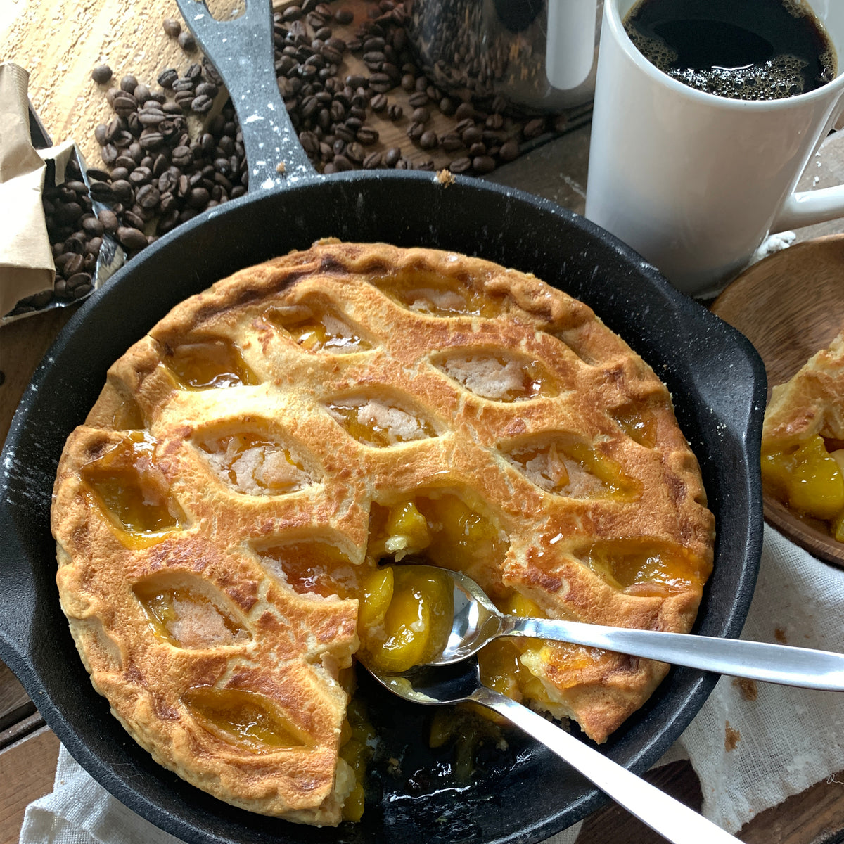 Cast Iron Skillet with a partially eaten apple pie with spoons and coffee