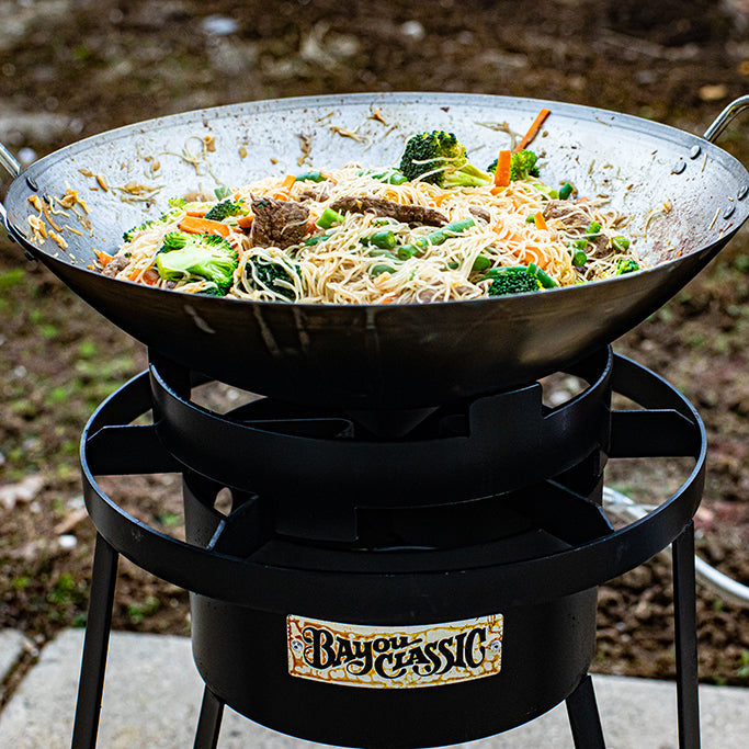 Wok with food on an outdoor cooker