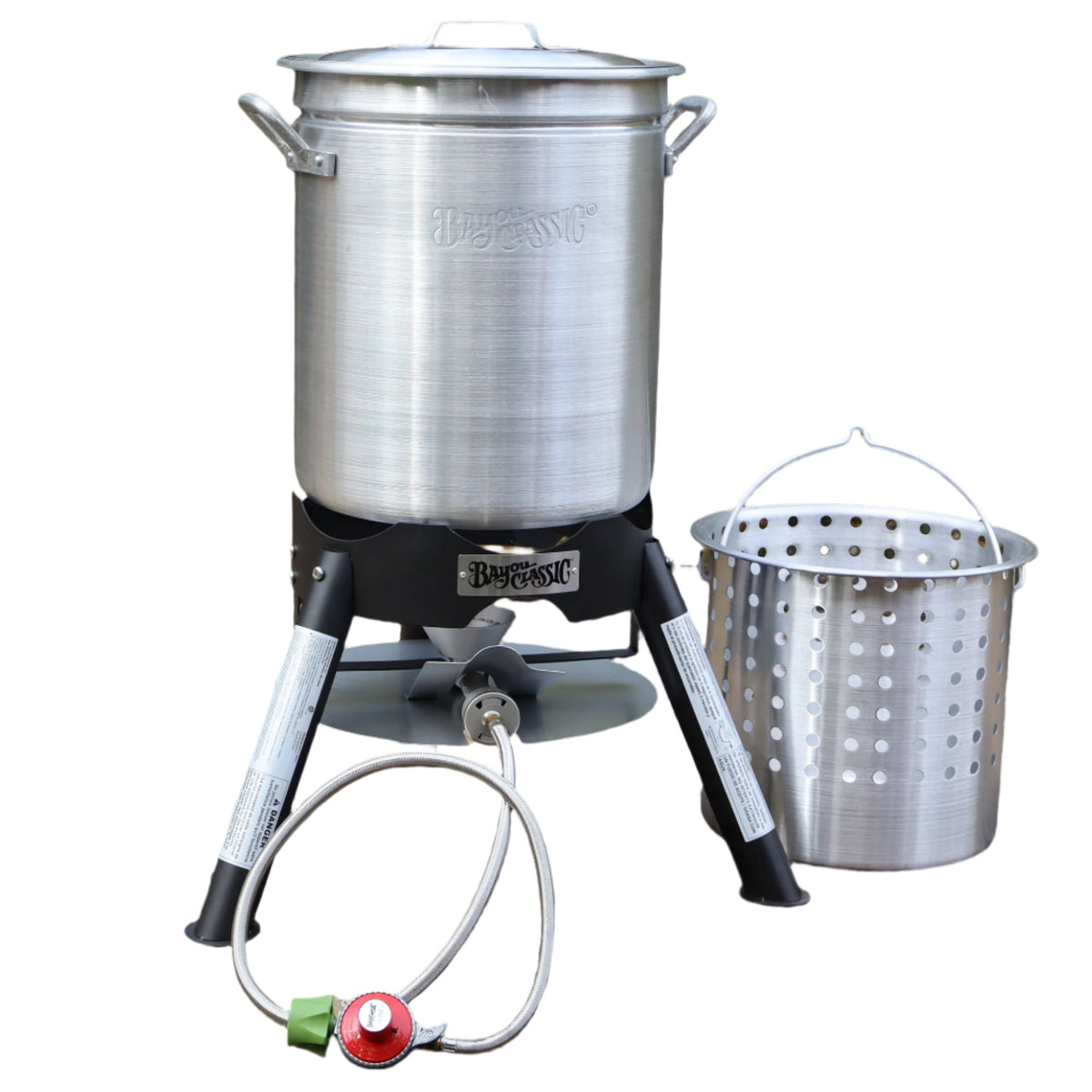 Aluminum Stockpot on an outdoor cooker with basket next to it on a white background