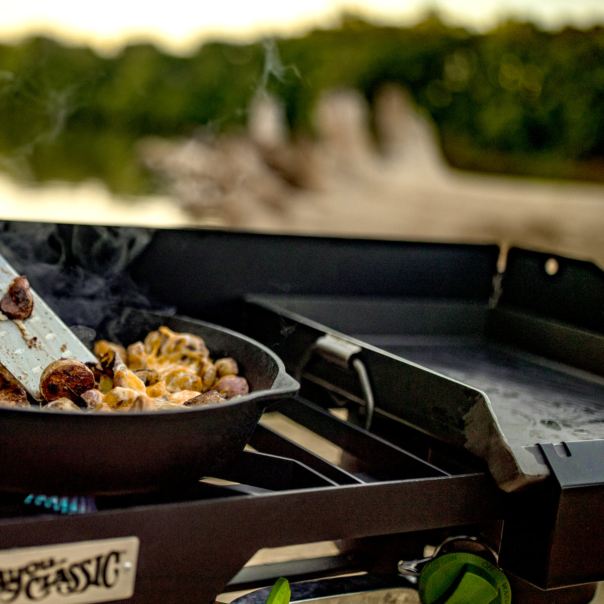 Cooking outdoors with a portable cooker and cast iron pan in a natural background