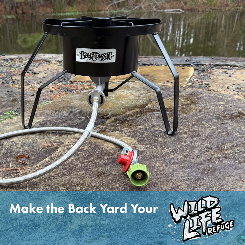 Black steel outdoor cooker with hose on a stone surface near water, with text that reads Make the Back Yard Your Wild Life Refuge