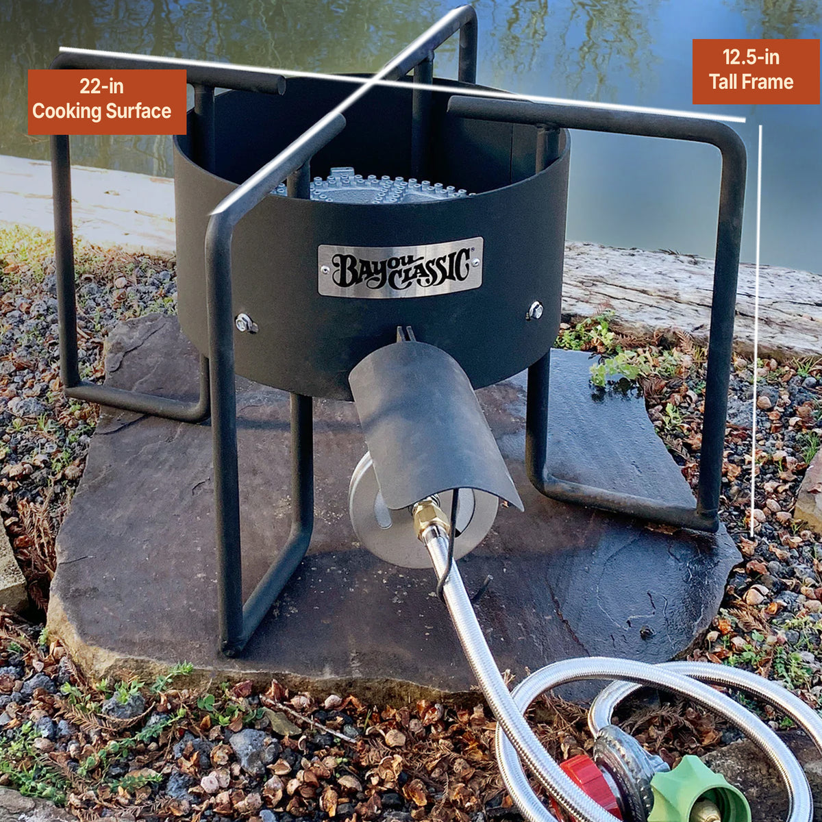 Black steel cooker outside by water with measurements that read 12-in tall frame and 22-in cooking surface