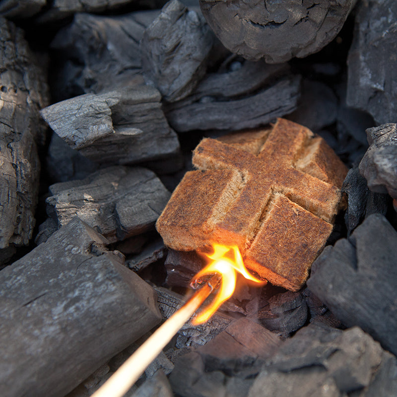 Natural firestarter being lit on top of lump charcoal