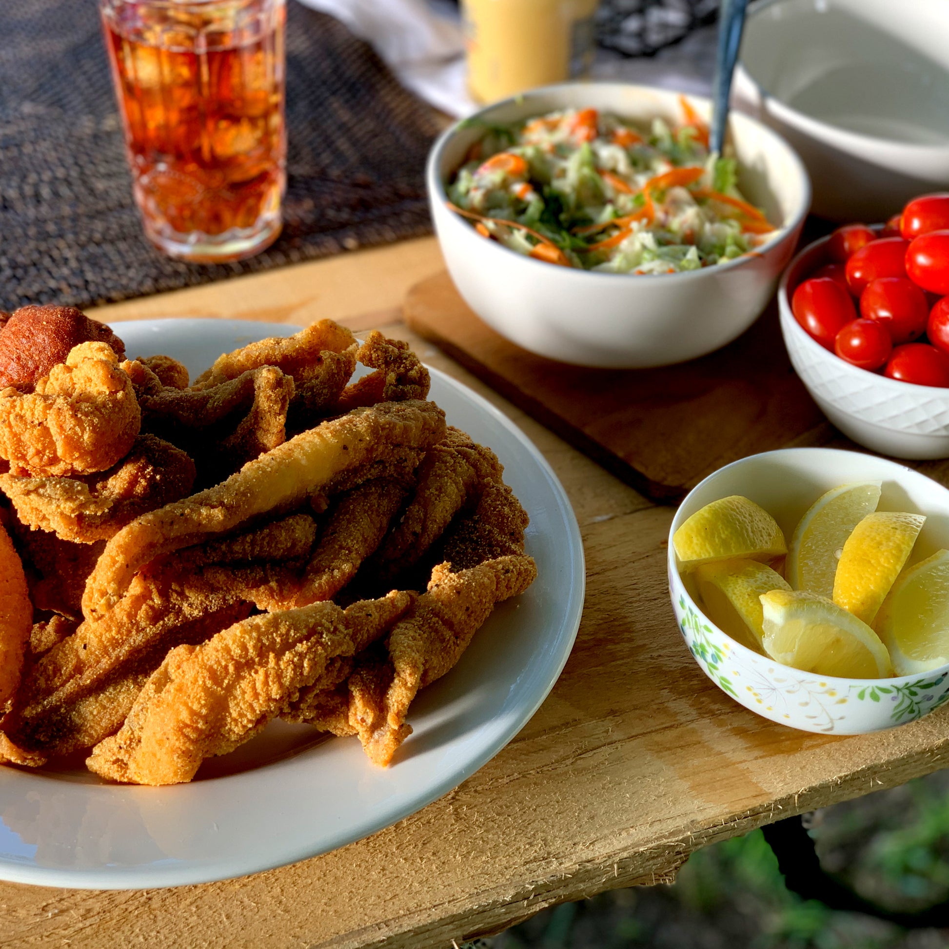 Fried fish on a plate next to a bowl of coleslaw with lemons