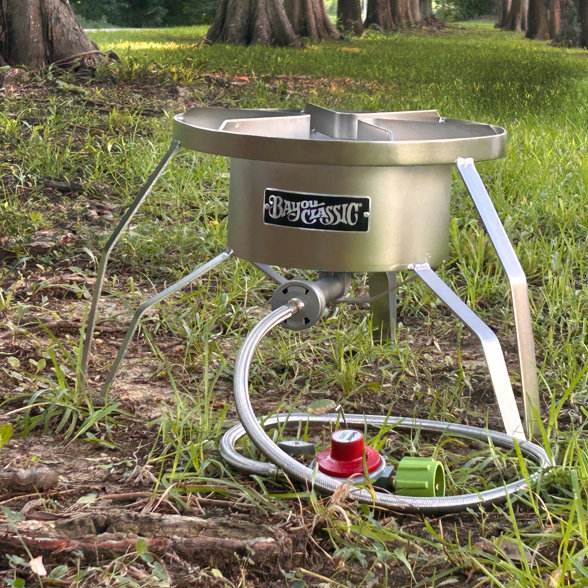Stainless steel outdoor cooker with Bayou Classic branding on a grassy outdoor setting.