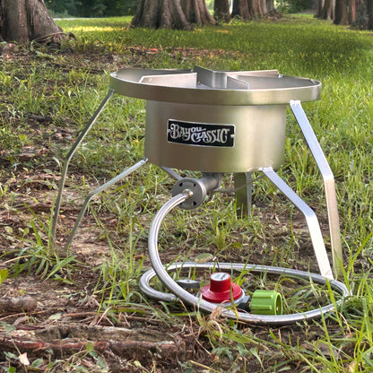 Stainless steel outdoor cooker with Bayou Classic branding on a grassy outdoor setting.