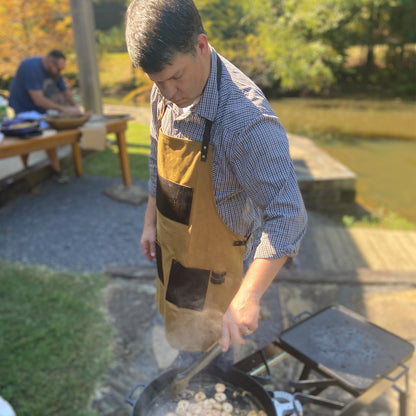 Person outside cooking in a brown apron