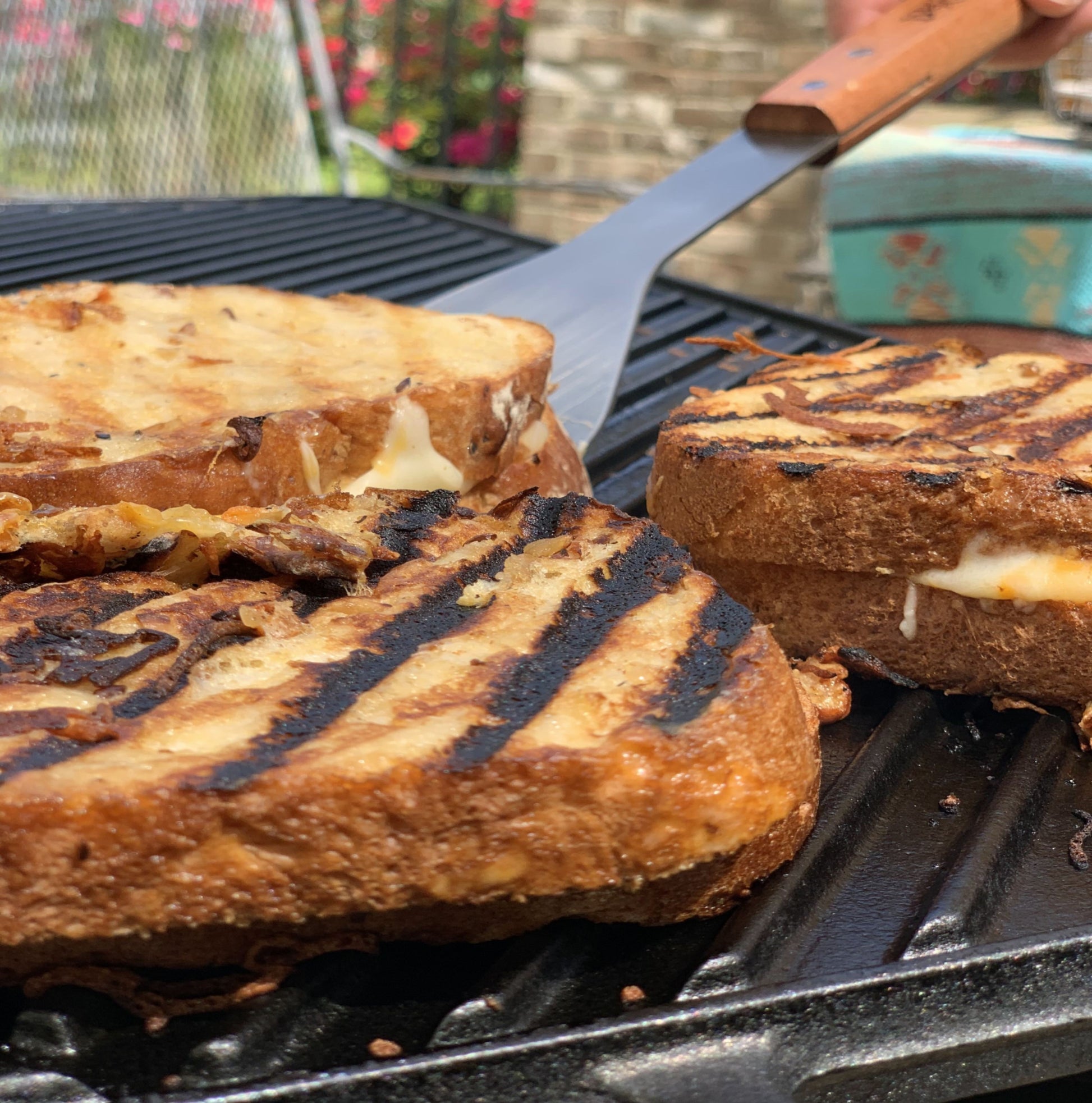Grilled cheese sandwiches being cooked outside on a cast iron griddle